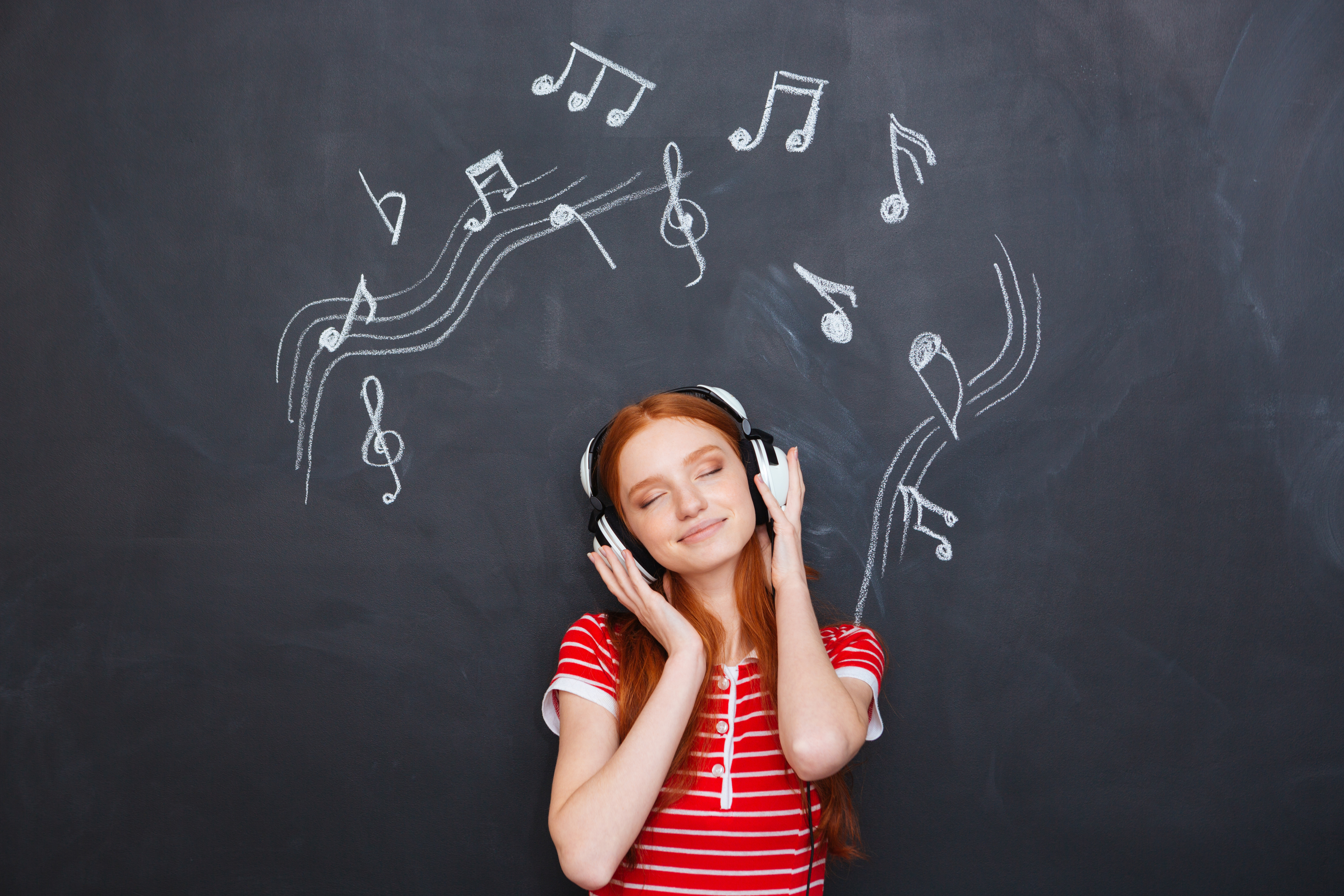 Relaxed smiling beautiful young woman listening to music in headphones